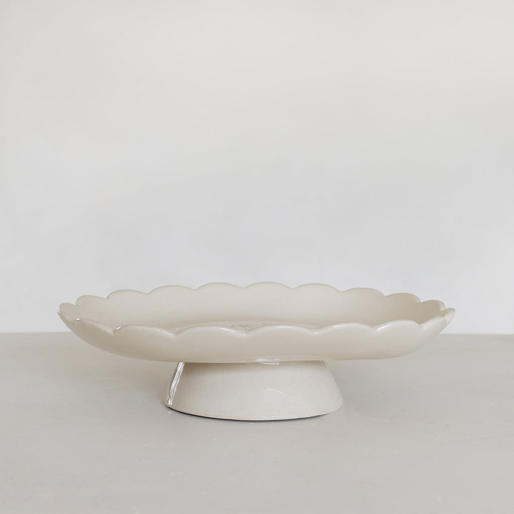 White ceramic cake stand on a light gray surface with a white background
