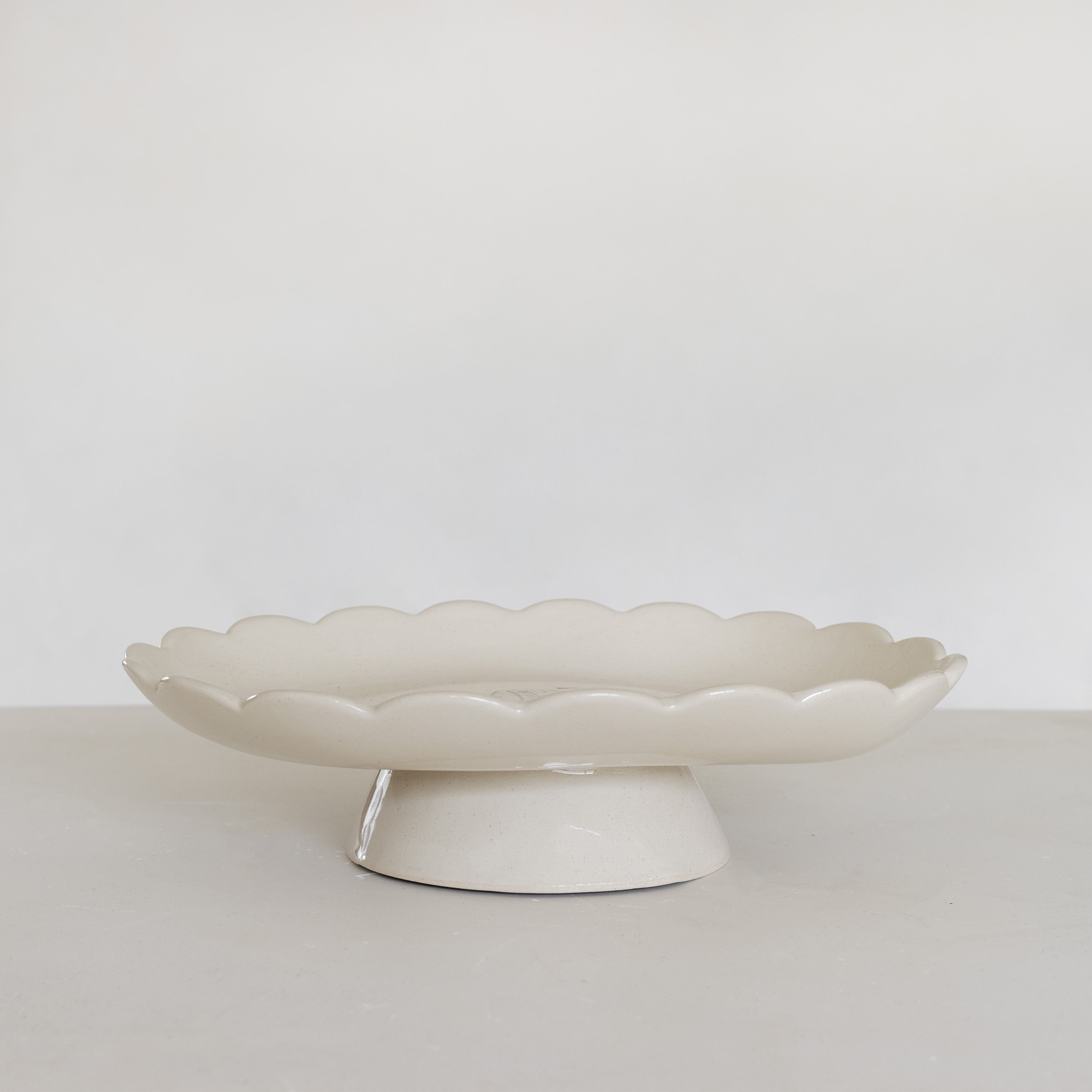 White ceramic cake stand on a light gray surface with a white background
