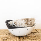 White colander with black interior on a woven mat