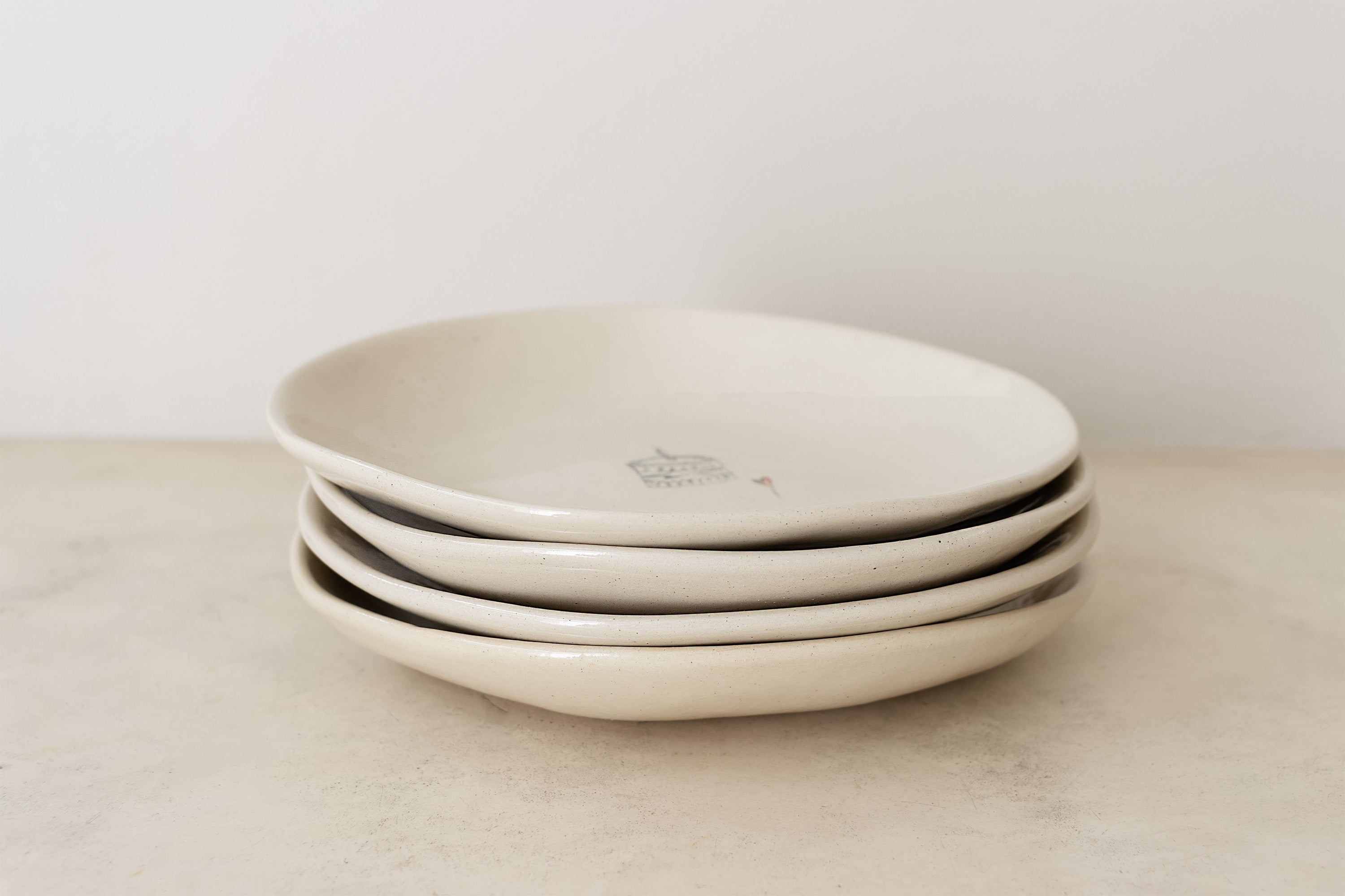Stack of beige ceramic plates on a light surface with a neutral background