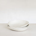 Two white ceramic bowls stacked on a light gray surface with a white background