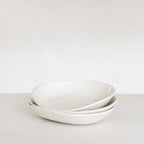 Two white ceramic bowls stacked on a light gray surface with a white background