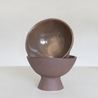Brown ceramic bowl stacked on a matching stand against a white background
