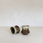 Two ceramic cups with textured surfaces on a white background