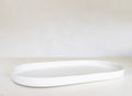 White oval tray on a light beige surface with a white background