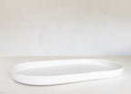 White oval tray on a light beige surface with a white background
