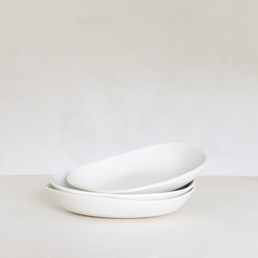 Stack of white ceramic bowls on a light gray background
