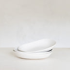 Stack of white ceramic bowls on a light gray background