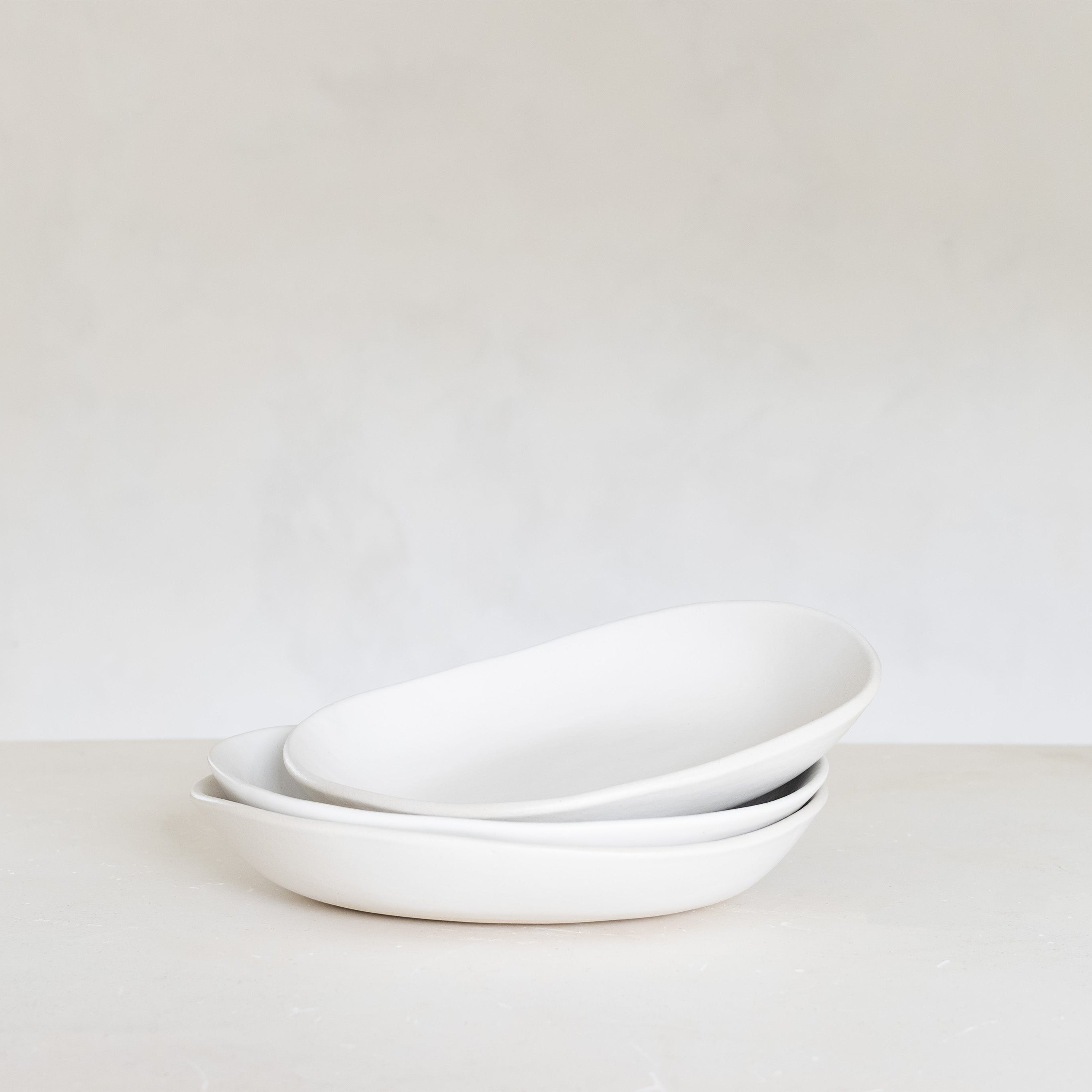 Stack of white ceramic bowls on a light gray background