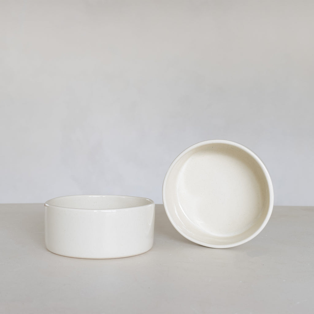 Two white ceramic bowls on a light gray surface with a plain background