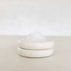 White ceramic jar with lid on a light beige surface with a white background