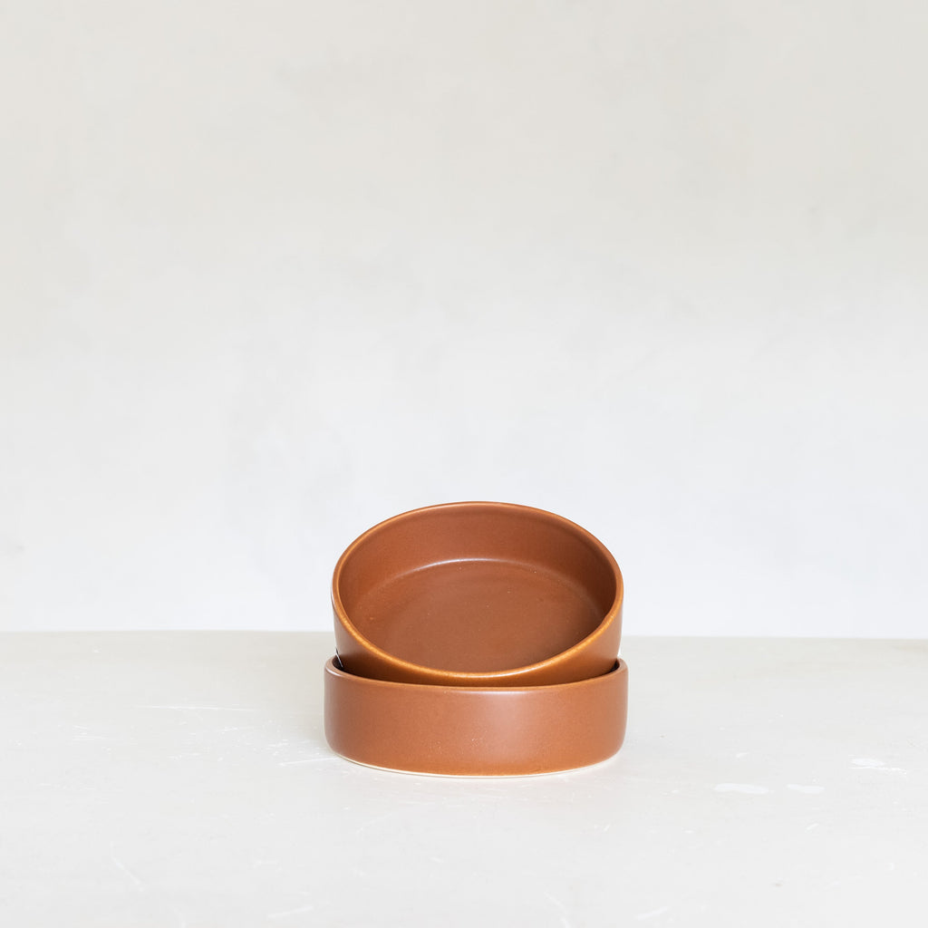 Two terracotta bowls stacked on a white surface with a white background