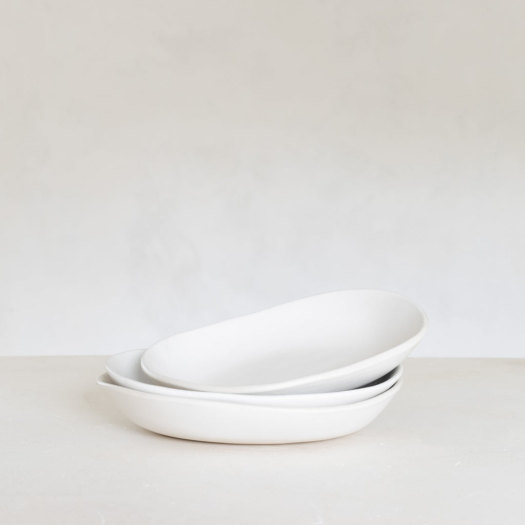 Stack of white ceramic bowls on a light gray background