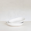 Stack of white ceramic bowls on a light gray background