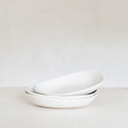 Stack of white ceramic bowls on a light gray background