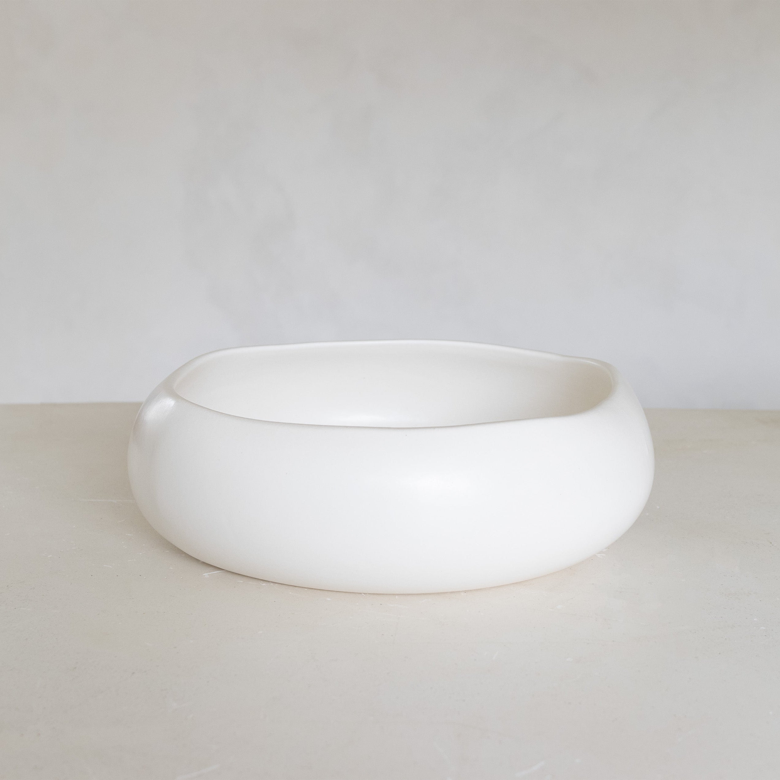 White ceramic bowl on a light gray surface with a white background