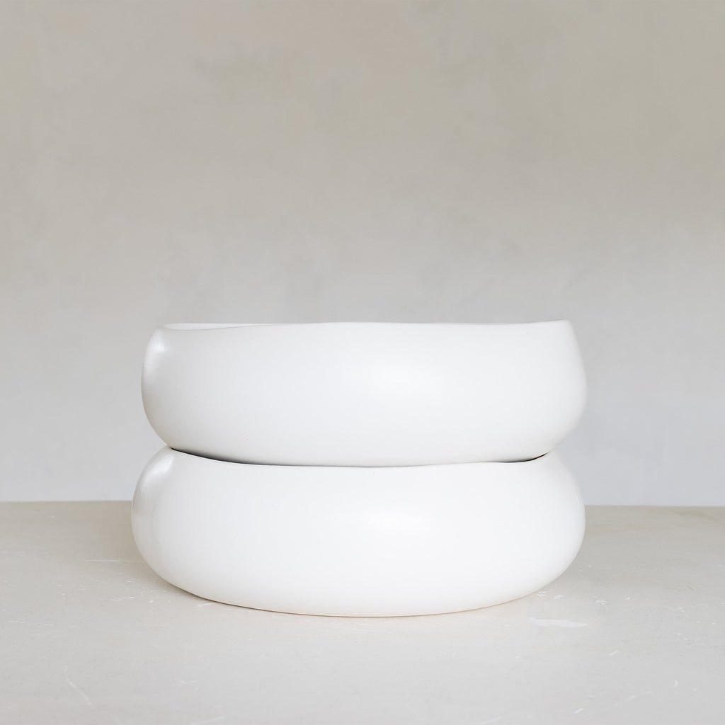 Two white ceramic bowls stacked on a light gray surface with a white background