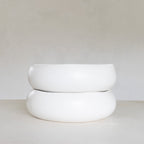 Two white ceramic bowls stacked on a light gray surface with a white background