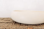 White ceramic candle on a woven bench with a white background
