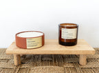 Two candles on a wooden stand with a neutral background