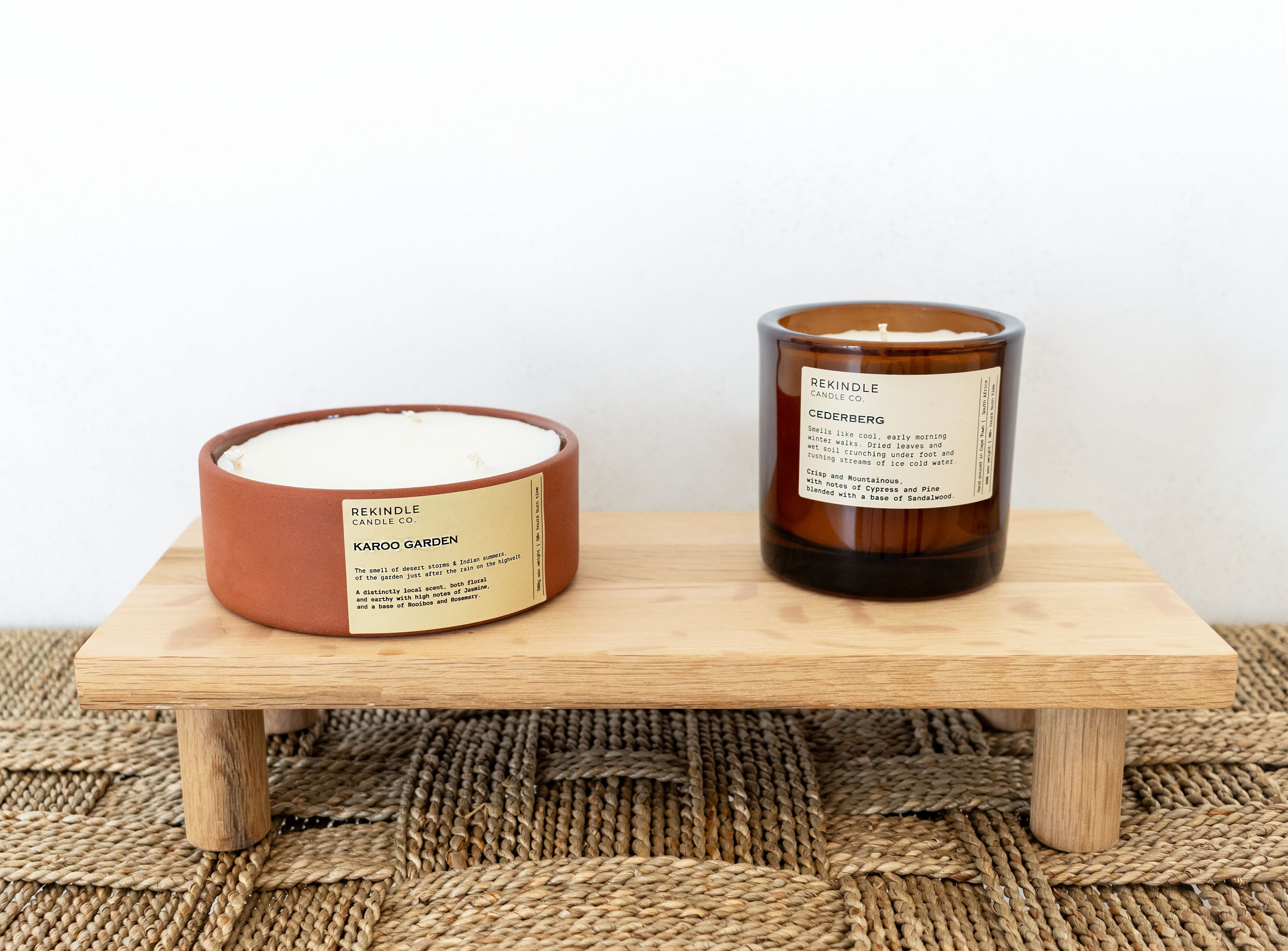 Two candles on a wooden stand with a neutral background