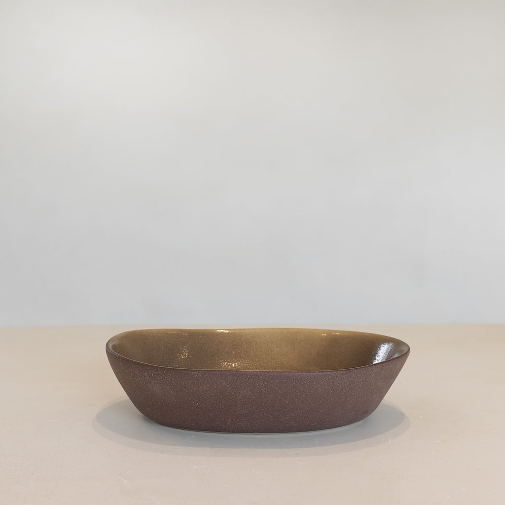 Brown ceramic bowl on a beige surface with a light gray background