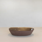 Brown ceramic bowl on a beige surface with a light gray background