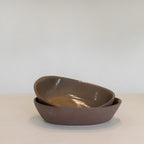 Two brown ceramic bowls stacked on a light surface with a white background