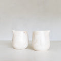 Two white ceramic jugs on a light gray background