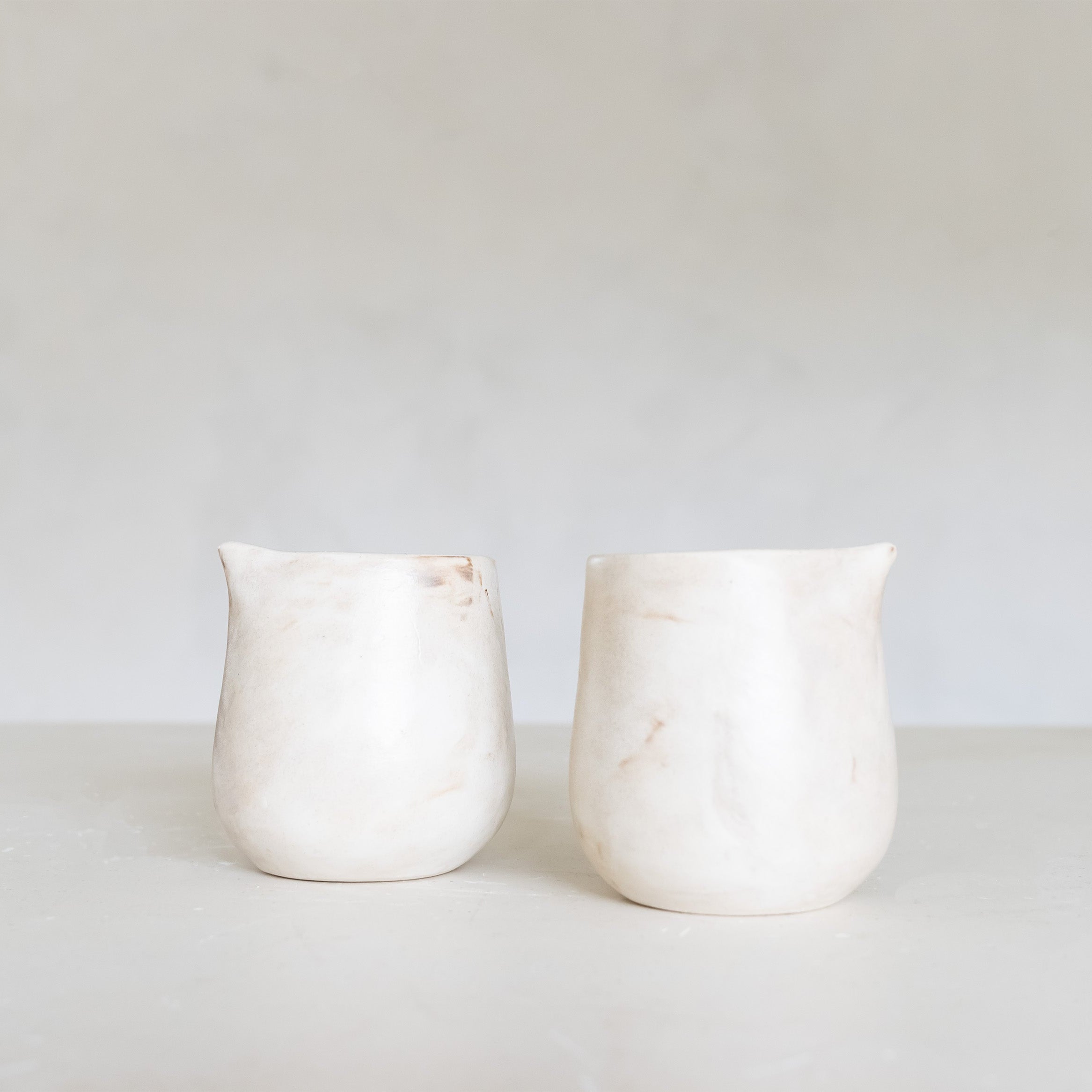 Two white ceramic jugs on a light gray background