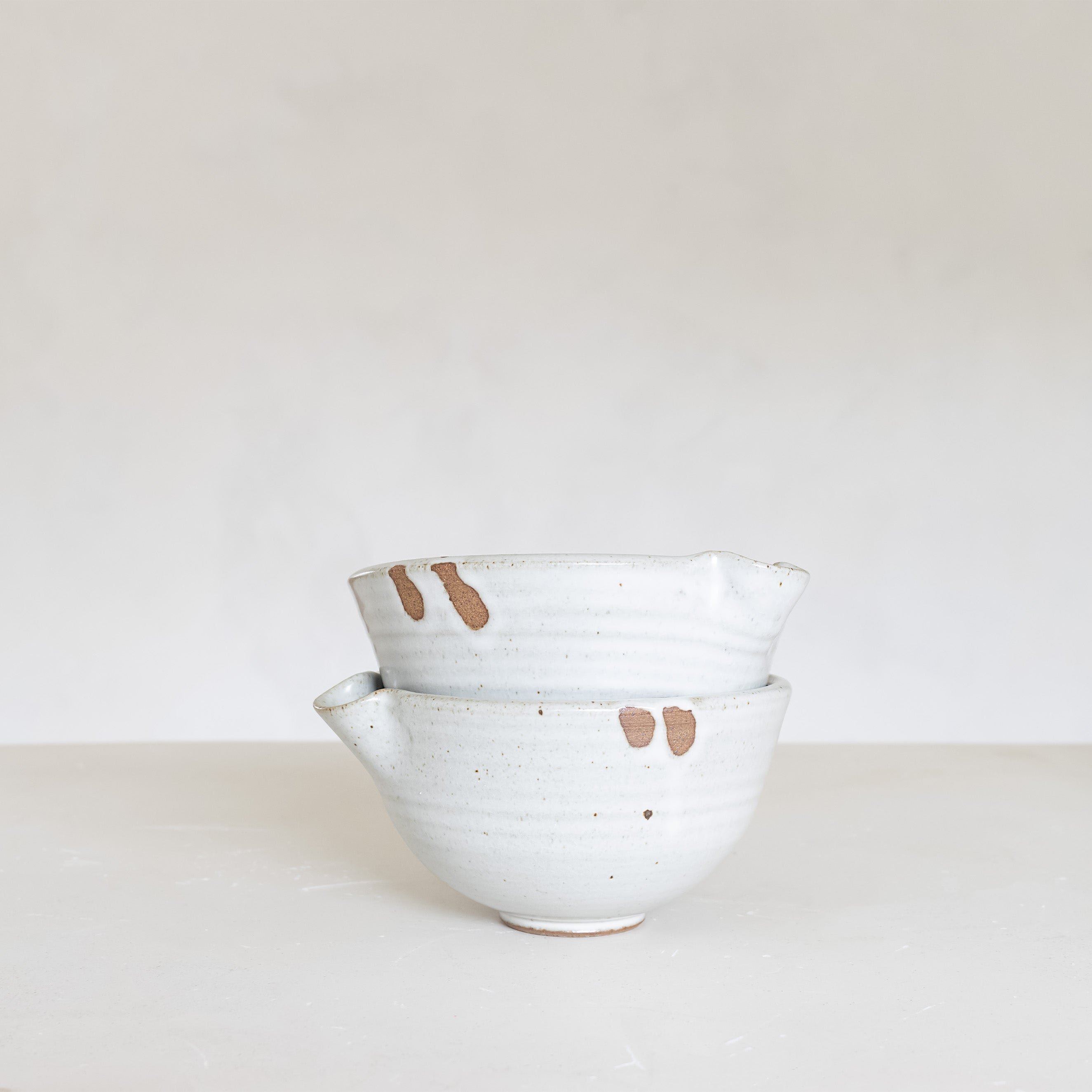 Set of ceramic bowls with brown speckles on a white surface and background