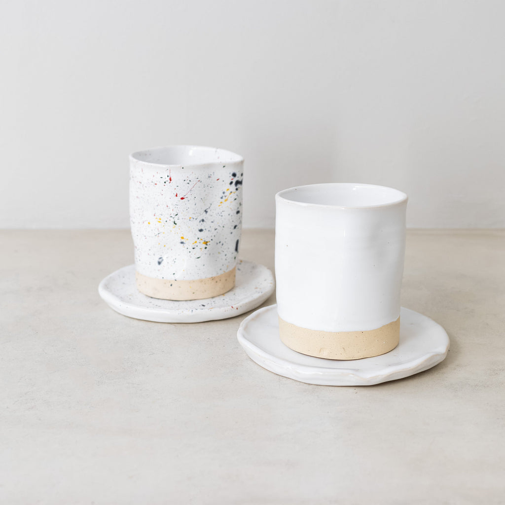 Two ceramic cups with saucers on a light surface with a neutral background