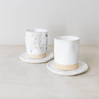 Two ceramic cups with saucers on a light surface with a neutral background