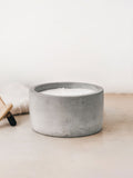 Trend{ING}s Raw Cement Candle with a towel and palo santo sticks beside it
